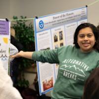 A student shares a poster presentation with two guests